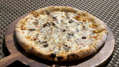 Closeup of Baked Truffle Pizza on Wooden Plate in Outdoor Cafe at Hot Sunny Day