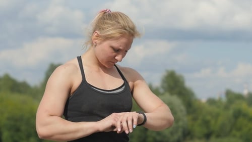 Woman Checking Fitness Data on Smart Watch Outdoors
