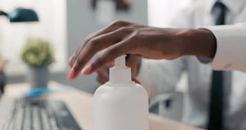 Man applies hand sanitizer then types at desk