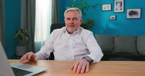 Diretor profissional maduro sentado em sua mesa em seu estúdio de escritório doméstico trabalhando em seu