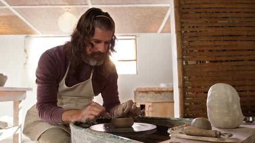 Bearded Man Crafts Clay Pot on Pottery Wheel