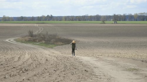Boy Walks Along the Path Through the Field
