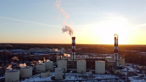 Thermal Power Plant Pipes with Smoke Against the Background of the Outgoing Sun in Winter