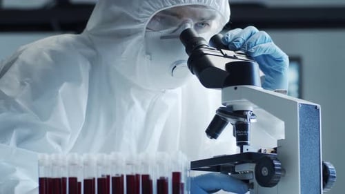 Researcher Examining Sample Through Microscope in Lab