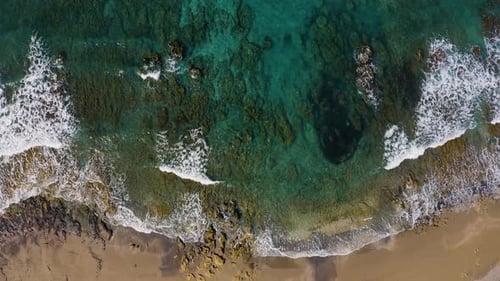 Vue aérienne des vagues de la mer s'écrasant contre une plage de rochers et de sable. Survolez la côte océanique