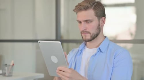 Young Adult Uses Tablet in Office