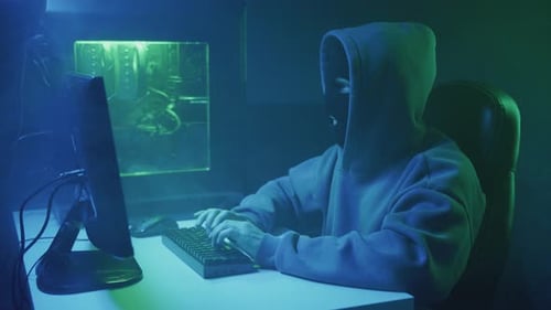 Masked Figure Typing at Computer in Dark Room