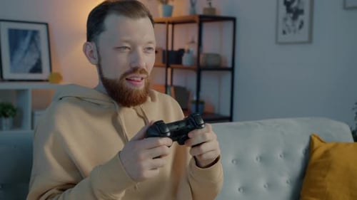 Man Plays Video Game on Couch at Home