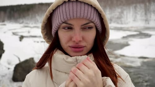A Young Girl Traveler in a Warm Jacket and Purple Hat Warms Her Frozen Hands