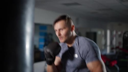 Portrait of Handsome Fit Male Boxer Hitting Punching Bag Training in Gym
