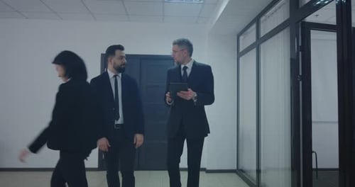 Two Men Walking and Discussing on Tablet Indoors