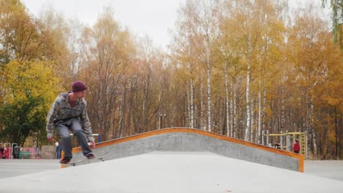 Skater Practicing in the Autumn Concrete Skate Park Making Tricks and Rides in Ramp