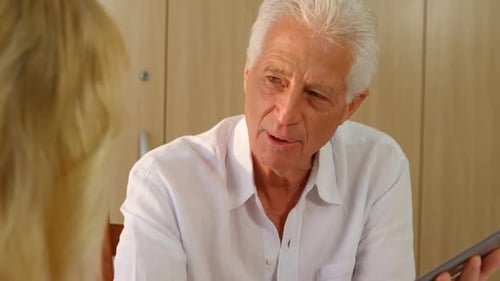 Senior Man Talking and Holding a Tablet Indoors