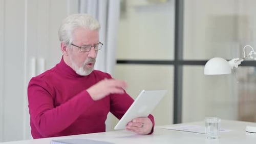 Senior Man Shocked Using Digital Tablet Indoors