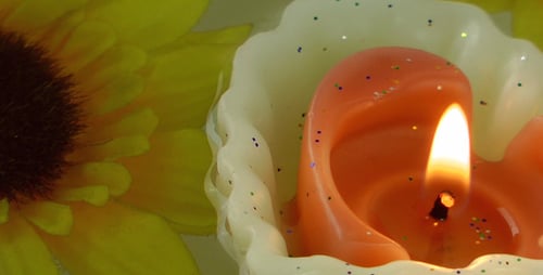 Bright Candles with Sunflower Petals Floating in Water