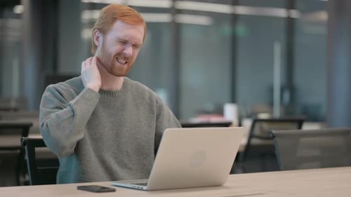 Young Man Having Neck Pain While Using Laptop in Office