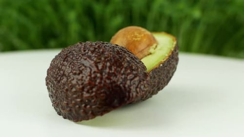 Avocado rotates on a green grass background. 4K video close-up of wholesome and healthy food.