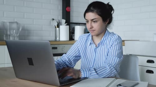 Woman Typing and Writing at Kitchen Table