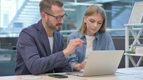 Businessman and Businesswoman Having Discussion on Laptop in Office