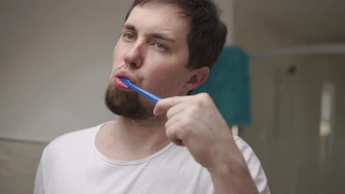 Young Man Is Brushing His Teeth By Toothbrush in Bathroom in Morning, Close-up