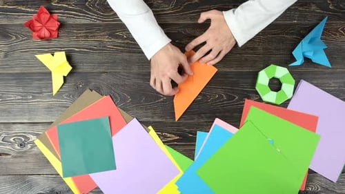 Mann faltet Papierblätter, während er Origami macht.