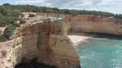 Aerial of a small, beautiful sand beach surrounded by tall cliffs