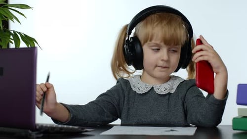 Cute Child with Laptop and Phone at Desk