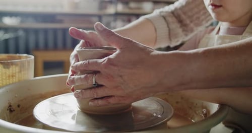 Child and Adult Shaping Clay on Pottery Wheel