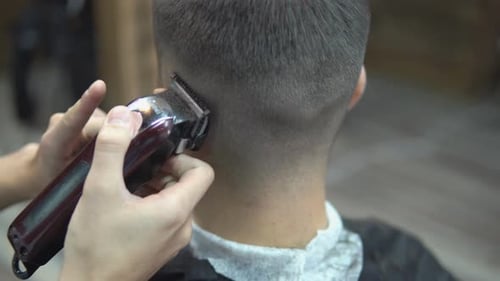 Meister schneidet Haare und Bart von Männern im Friseurladen, Friseur macht Frisur für einen Mann