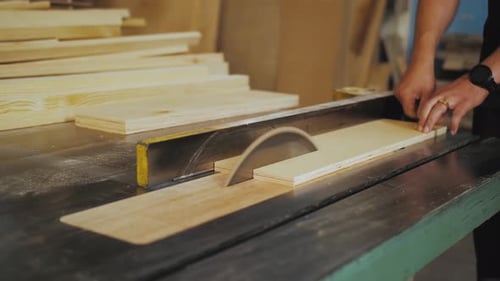 A Running Blade on a Bench Saw Sawing Trough the Wooden Log in the Middle of a Working Space Close