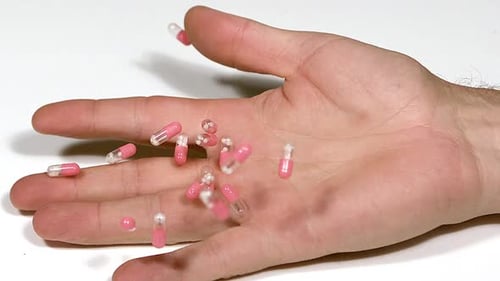 700364 Fallende Hand eines Mannes mit Morphinkapseln auf weißem Hintergrund, Zeitlupe