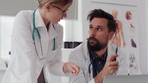 Handheld view of two busy doctors using a laptop