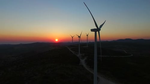 Aerial view of windmills with slowly rotating blades at sunset