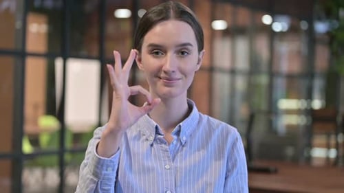 Young Woman Giving Ok Sign in Modern Office