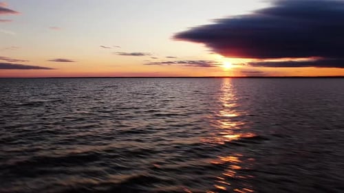 Ein langer Strahl von der untergehenden Sonne reflektiert das Meer in dynamischer Bewegung. Über das Meer bei Sonnenuntergang fliegen