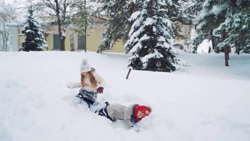Two little girls crawling in the snow on the forest background in winter.