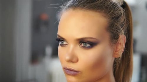 Nahaufnahme eines Friseurs, der Haarspray auf ein Model sprüht, während er eine Frisur macht