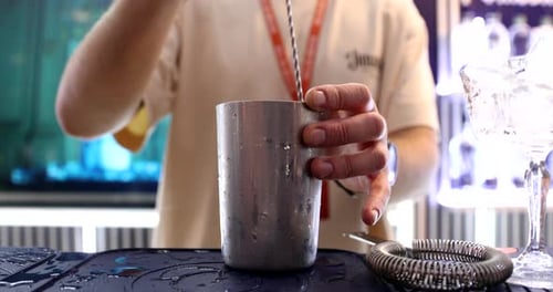 Bartender Mixing Refreshing Cocktail with Spoon in Shaker