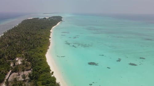 Flight over the Maldivian island washed on both sides by turquoise water