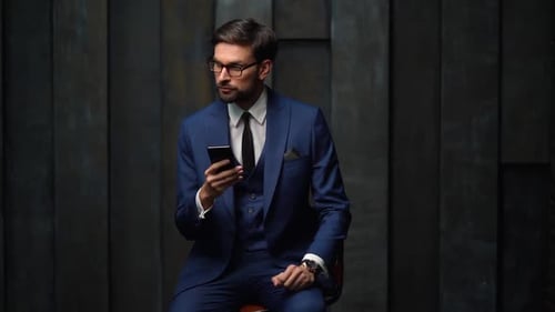 Adult Man in Suit Looks at Phone