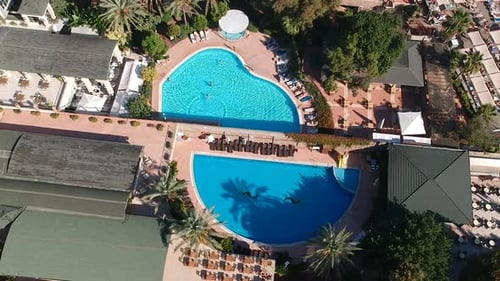 Drohnenaufnahme aus der Luft von Hotelgärten und Schwimmbädern in einem sonnigen Resort.