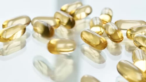 Yellow Capsule Falling on Glossy White Table Surface Slow Motion
