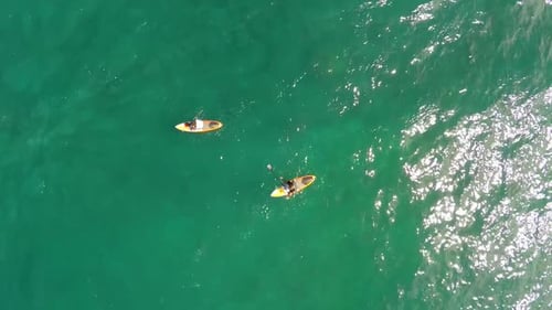 Aerial view of two men sup stand-up paddleboard surfing in Hawaii