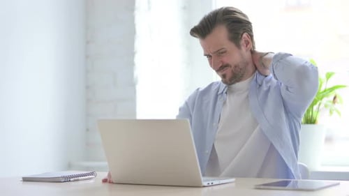Man Typing on Laptop Rubs Neck in Discomfort