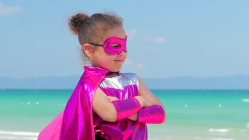 Young Girl in Superhero Costume on Beach