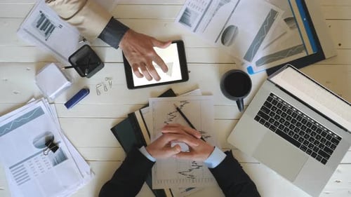 Top View Male Hands of Two Coworkers Checking Graphs with Statistics and Discussing Financial