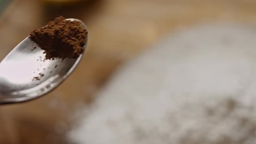 Gloved Hand Adding Powder to Glass Bowl