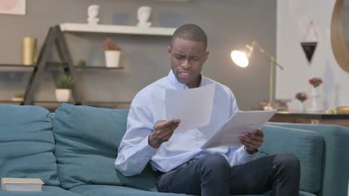 Frustrated Man Looking at Documents on Couch