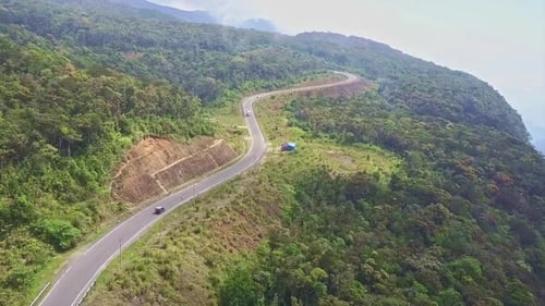 Drohne fliegt entlang der modernen Bergstraße inmitten des Waldes