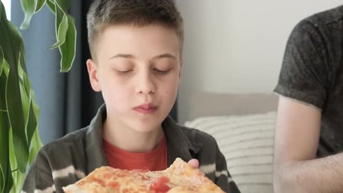 Boy Eating Pizza Slice at Home Indoors